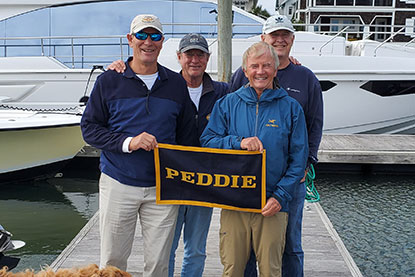 Men stand on a dock and hold a Peddie sign.