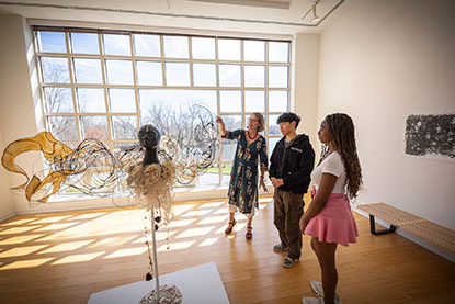 A teacher talking about a sculpture with two students. Links to Gifts from Retirement Plans